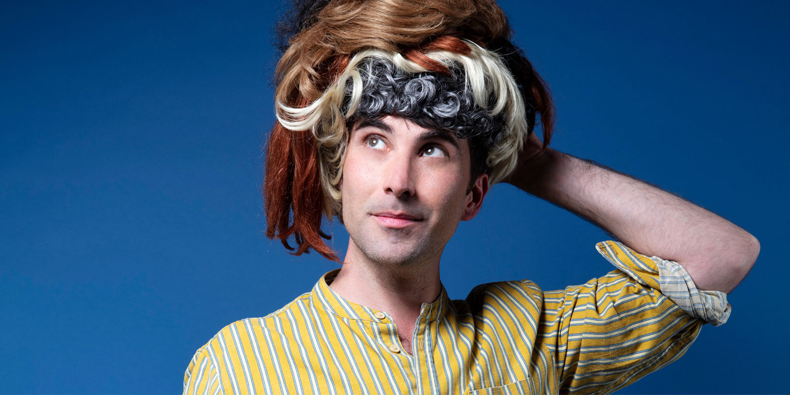 Photo de Thomas Poitevin avec des perruques sur la tête.